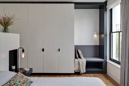 White fitted wardrobes in bedroom with custom, upholstered window seat