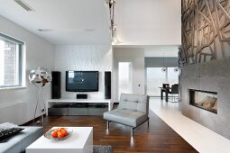 Künstlerischer Kaminbereich in offenem Wohnraum, Loungebereich mit Fernseher und Designerstehleuchte