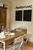 Breakfast ingredients on table next to blackboards and motto on wall in vintage-style dining area