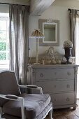 Antique armchair next to grey chest of drawers in vintage interior with French ambiance