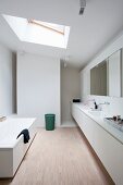 Eingebaute Waschtischzeile mit zwei Waschbecken, im Hintergrund Duschbereich, Dachflächenfenster und weiße Badewanne