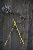 Stricknadeln mit aufgenommen Maschen aus Öko-Wolle auf altem Holztisch