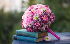 Romantischer pinkfarbener Brautstrauß auf antiquarischen blauen Büchern arrangiert