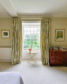 Tray table in front of lattice window with floor-length curtains in bedroom
