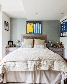 Elegantes Schlafzimmer mit Doppelbett und Kopfteil, an Wand gerahmte Sporttrikots und Pokalsammlungen auf Nachtkästchen