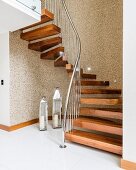 Winding staircase with wooden treads and stainless steel balustrade above lanterns on tiled floor