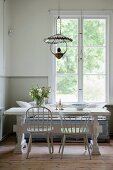 Pale grey chairs and vintage table in dining area below lattice window