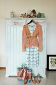 Vintage wardrobe painted pale blue decorated with vintage china ornaments and woman's clothing