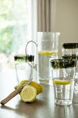 Zitronen und mit Wasser gefülltes Glas auf Tisch mit Wasserkrug