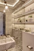 Elegant bathroom with marble sink on tiled wall and strip lights integrated into shelves