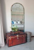 Old trunk in front of latticed arched mirror in bedroom