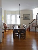 Dark wooden dining table and chairs in traditional dining room with staircase to one side