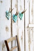 Hand-decorated deer antlers on turquoise wooden plaque on shabby-chic board wall