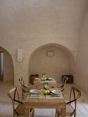 Wooden chairs at set table in Mediterranean dining room of Apulian trullo