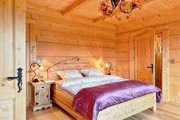 Double bed with curved headboard and purple silk cover in solid wooden house