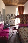 Pink sofa opposite daybed with ethnic blanket in eclectic ambiance