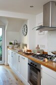 Long wooden kitchen worksurface with extractor hood above gas cooker
