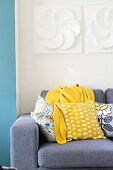 Colourful scatter cushions and blanket on grey sofa