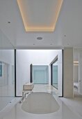 Designer bathtub below ceiling panel with indirect lighting in modern house with atrium