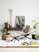 Designer armchair and footstool with pale upholstery amongst house plants