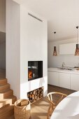 Fire in white fireplace with firewood store in modern interior