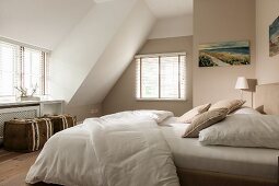 Beige bedroom with double bed and pouffes in converted attic