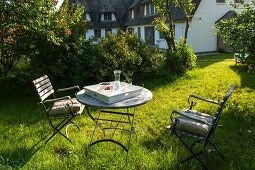 Two chairs and round table in sunny garden