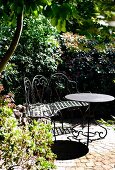 Filigrane Sitzbank und Tisch aus Metall in sonnigem Garten