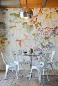 Round table and metal chairs in front of floral wallpaper