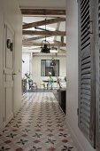 Flur mit Ornamentfliesen und Blick in offenen Wohnraum mit rustikalen Fachwerkträgern