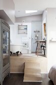 View from bedroom into open-plan bathroom with free-standing bathtub and rustic washstand on platform accessed via steps