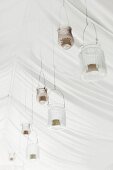 Festliche Hochzeitsdekoration aus Windlichtern aufgehängt an weißem Zeltdach