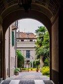 View through arch into Mediterranean courtyard with open gate