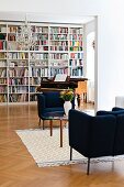 Loungebereich vor antikem Klavierflügel und raumhoher Bücherwand in Altbauwohnung