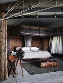 African style bedroom with straw walls and modern mosquito canopy