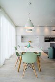 Dining table and mint-green shell chairs in white designer kitchen