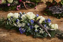Alpine-style arrangement of roses, gentian, antlers and conifer branches