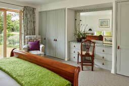 Schlittenbett mit Holzgestell und hellgraue Einbauschränke mit integriertem Schminkplatz im Schlafzimmer