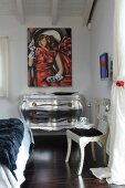 Silver chest of drawers with curved front and legs below modern painting