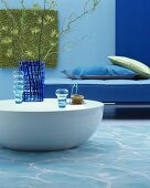 Blue glass vases on sold round coffee table in front of blue sofa