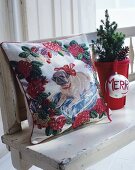 Embroidered cushion with dog motif, miniature tree and bauble on white, shabby-chic bench
