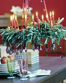 Festive wreath of olive branches, lit red candles and purple crystal pendants hung from ribbons