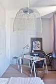 Lampshade hand-crafted from chicken wire above desk on trestles