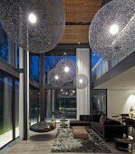 Enormous spherical lampshades and suspended fireplace in double-height, futuristic living room