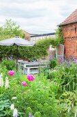 Blooming cottage garden with seating area next to brick barn