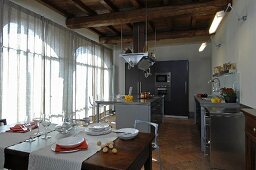 Moderne offene Küche unter rustikaler Holzbalkendecke in renoviertem Landhaus