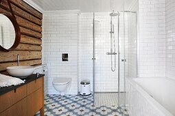 Rustic log-cabin wall, bathtub and glazed shower cubicle in bathroom