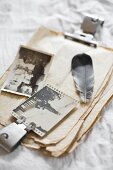 Feather and old photos on stack of vintage paper