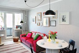 Round white dining table, red sofa and gallery of pictures in living room