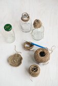 Balls of string, crochet hook and glass bottles with crocheted trim